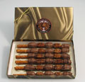 Big Daddy Pretzel Rods | 6 Piece Box - Pretzel rods are covered in creamy caramel with pecan halves or whole almonds and dipped in milk chocolate.  A second covering of pecans or almonds are layered again and then drizzled with dark chocolate.  Six wrapped pretzel rods in a signature box.